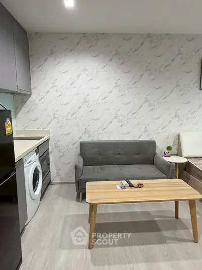 Modern living room with compact sofa, washing machine, and stylish marble wallpaper.