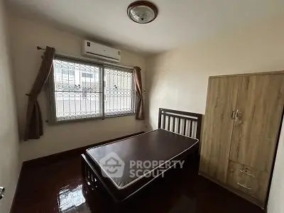 Cozy bedroom with wooden furniture and air conditioning in a well-lit space.