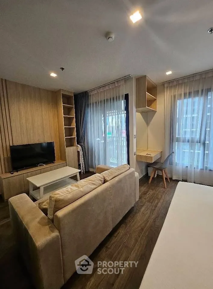 Modern living room with cozy sofa, TV, and study area in stylish apartment.