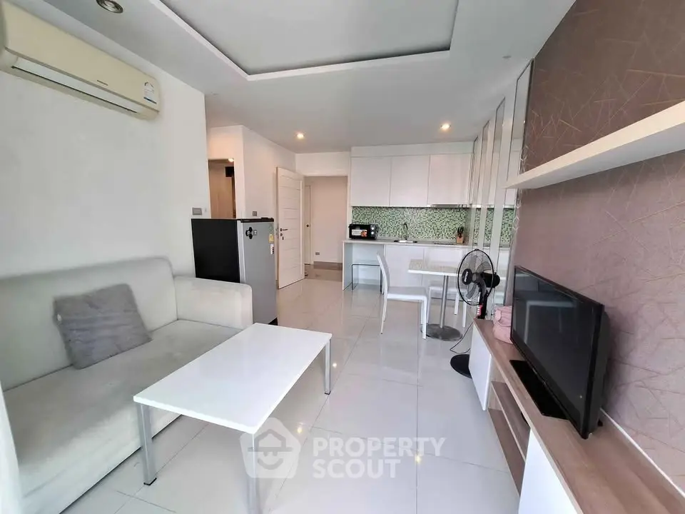 Modern open-plan living room with sleek kitchen, white furniture, and stylish decor.
