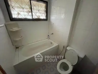 Cozy bathroom with bathtub and tiled walls, ideal for a relaxing soak.