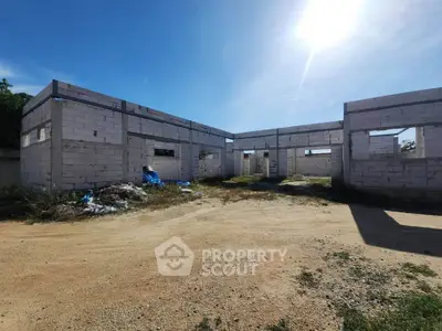 Unfinished construction site with exposed brick walls under a clear blue sky, showcasing potential for development.