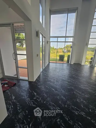 Spacious modern living room with high ceilings and large windows offering stunning garden views.