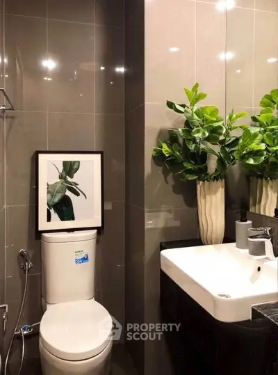 Modern bathroom with sleek fixtures and stylish decor, featuring a framed plant artwork and lush greenery.