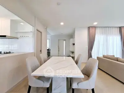 Modern dining area with marble table and elegant chairs in open layout living space.