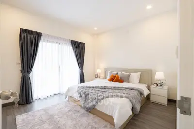 Elegant bedroom with cozy decor and natural light through large window.