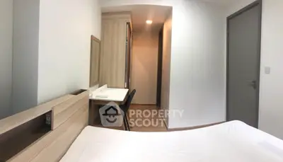 Modern bedroom with minimalist design, featuring a cozy bed and a sleek study area.