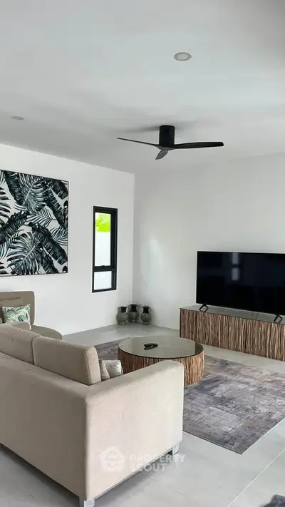 Modern living room with stylish decor, featuring a large TV, comfortable sofa, and contemporary ceiling fan.