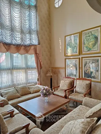 Elegant living room with high ceilings, luxurious drapes, and classic art decor.