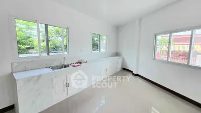 Spacious kitchen with large windows and sleek countertops in a modern home.