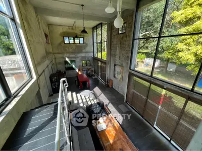 Spacious industrial-style living room with large windows and garden view