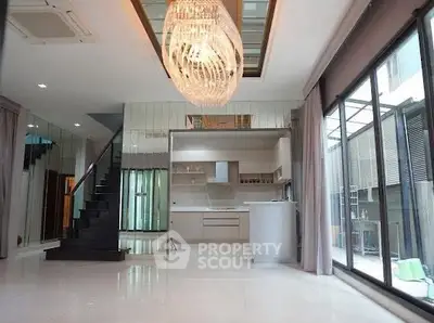 Luxurious modern living room with elegant chandelier and open kitchen layout