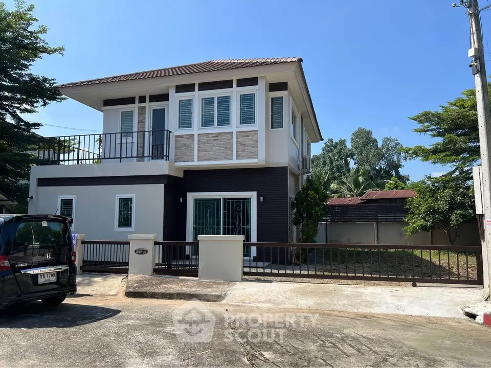 Modern two-story house with balcony and spacious driveway in serene neighborhood.