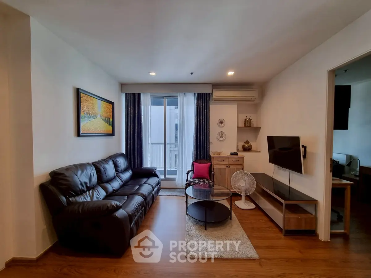 Modern living room with leather sofa and wall-mounted TV, featuring elegant decor and natural light.