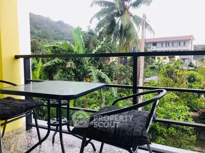Charming balcony with lush green views and cozy seating, perfect for relaxation.