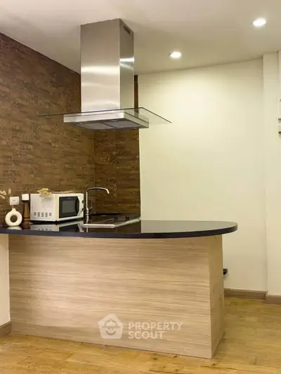 Modern kitchen with sleek design, featuring a microwave and stylish range hood.