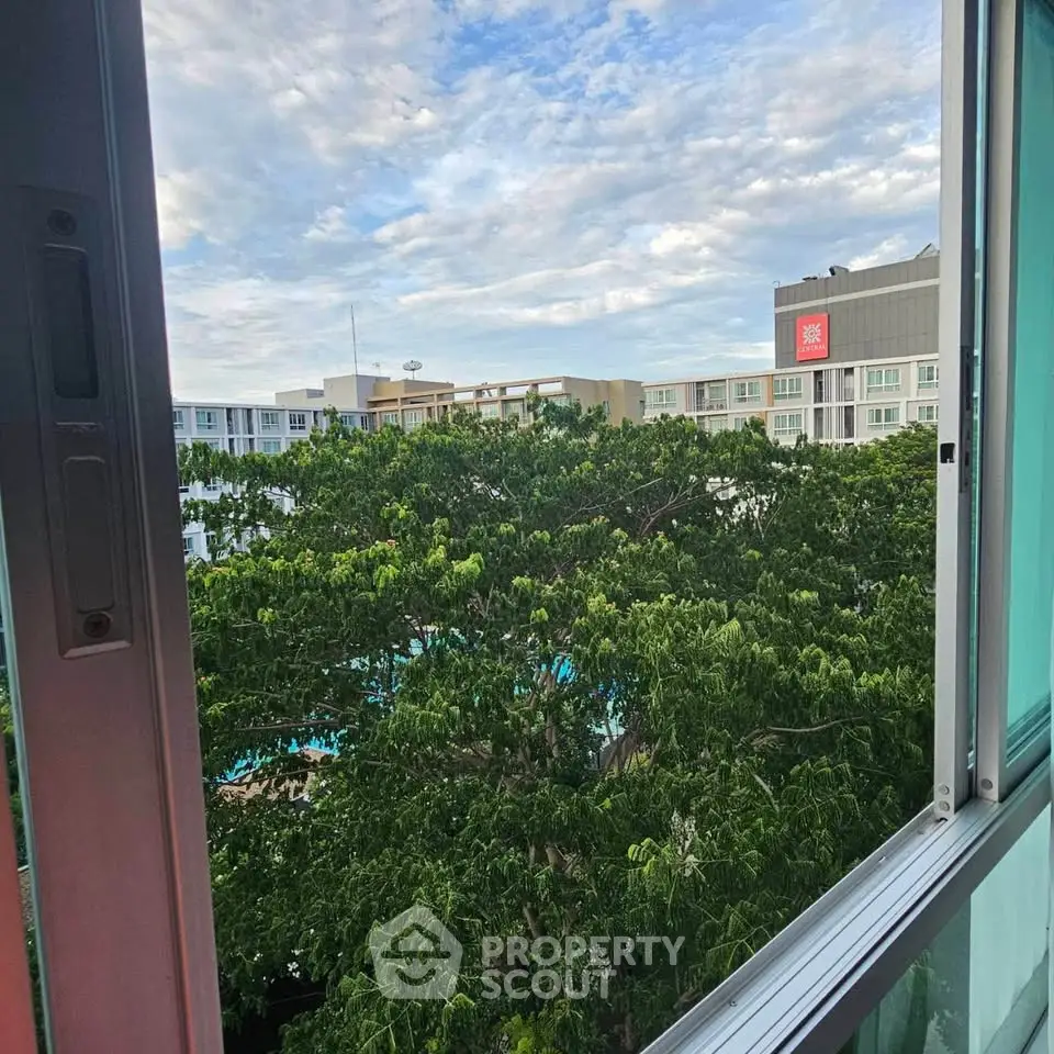 Scenic view from a window overlooking lush greenery and modern buildings.