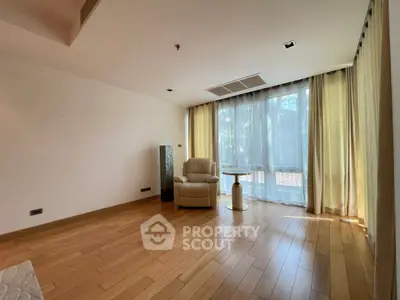 Spacious living room with wooden flooring and large windows for natural light.