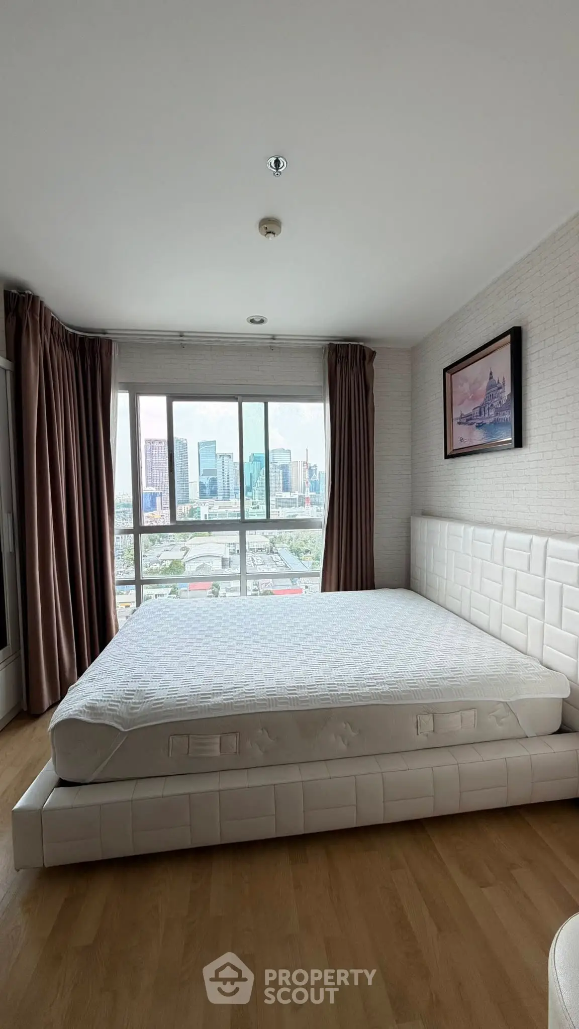 Spacious bedroom with large window offering stunning city view