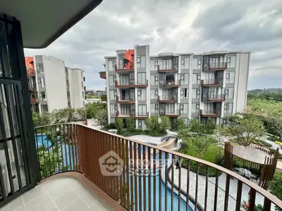 Modern apartment balcony with pool and garden view in a contemporary residential complex.