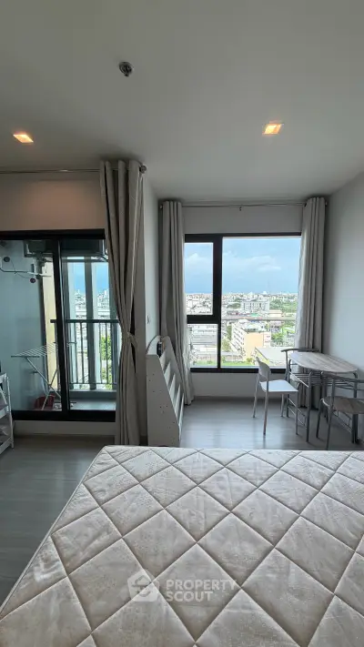 Spacious modern bedroom with large windows offering stunning city views and ample natural light.