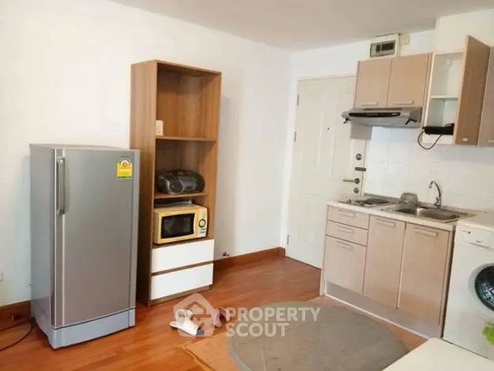 Cozy kitchen with modern appliances and wooden flooring in a compact apartment.