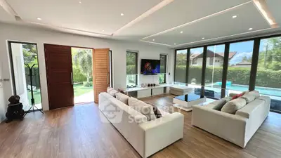 Spacious modern living room with large windows and garden view, featuring elegant sofas and stylish decor.