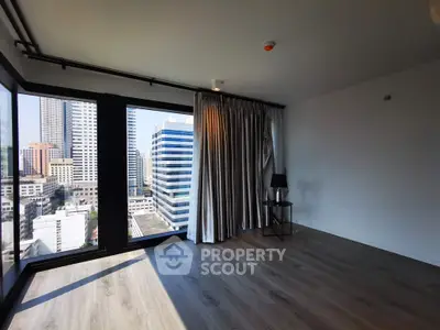 Spacious modern living room with floor-to-ceiling windows offering stunning city views.