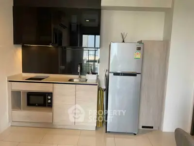 Modern kitchen with sleek cabinetry, built-in microwave, and stainless steel fridge in a compact layout.