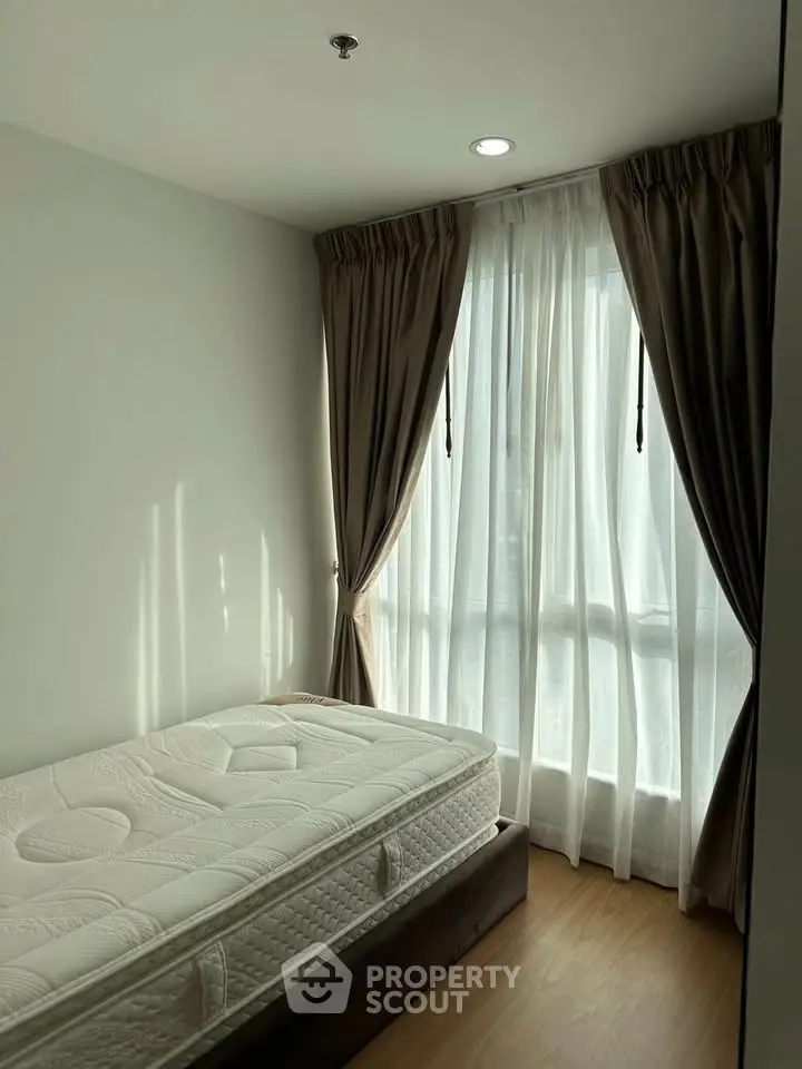 Cozy bedroom with natural light and elegant curtains in modern apartment.