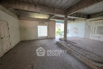Spacious unfinished interior with potential for renovation, featuring concrete floors and exposed beams.