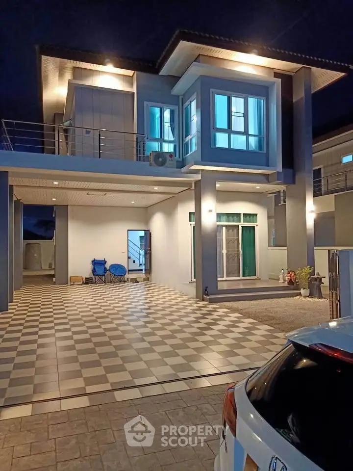 Modern two-story house with spacious driveway and elegant exterior lighting at night.