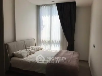 Cozy bedroom with natural light and elegant curtains, perfect for relaxation.