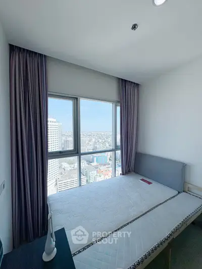 Modern bedroom with panoramic city view and large windows in high-rise apartment.