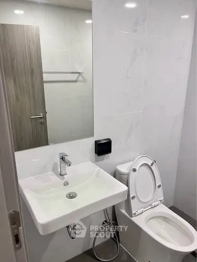 Modern bathroom with sleek white fixtures and marble wall tiles.