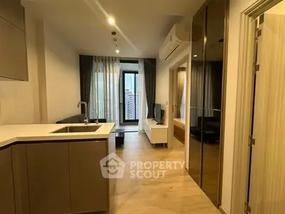 Modern apartment interior with open kitchen and living area, featuring sleek design and large windows.