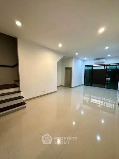 Spacious modern living room with sleek tile flooring and ambient lighting