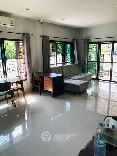 Spacious living room with modern furniture and large windows offering garden views.