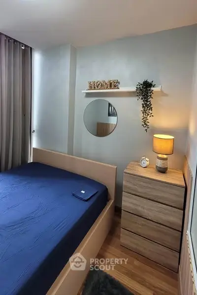 Cozy bedroom with modern decor, featuring a stylish bed, wooden dresser, and ambient lighting.