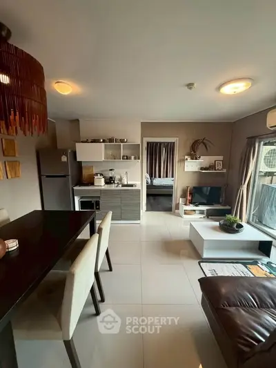 Modern open-plan living room with kitchen and dining area, featuring stylish decor and natural light.