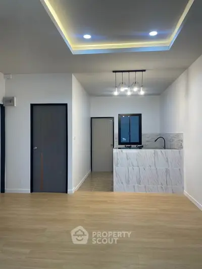 Modern interior with sleek lighting and open layout, featuring a stylish kitchenette and wooden flooring.