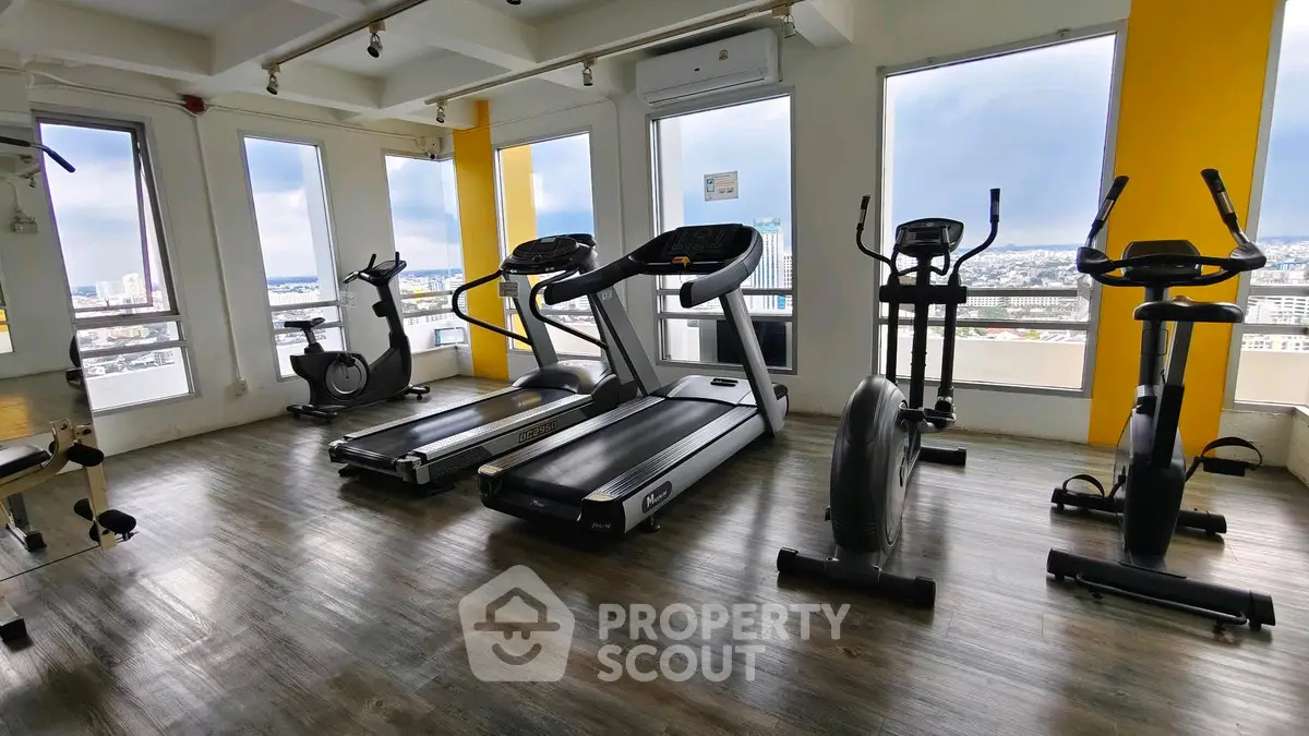 Modern gym with city view featuring treadmills and exercise bikes.
