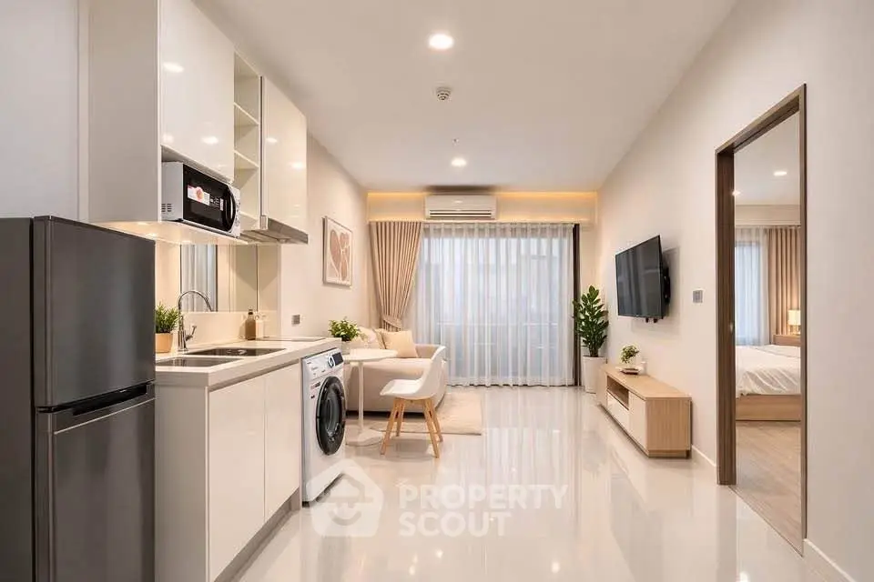 Modern open-plan living room with sleek kitchen and cozy bedroom view, perfect for urban living.