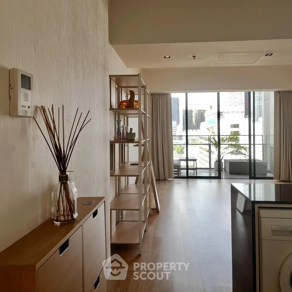 Spacious modern living room with balcony and city view, featuring elegant decor and natural light.