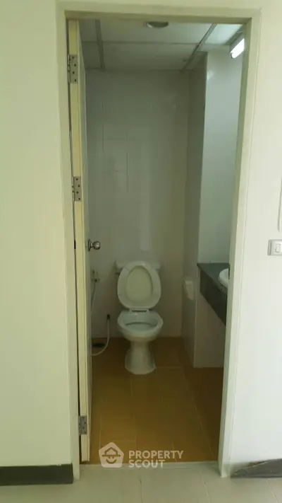 Compact bathroom with white toilet and tiled floor in modern apartment.
