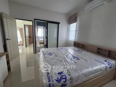 Spacious bedroom with modern design and natural light, featuring a new mattress and air conditioning.