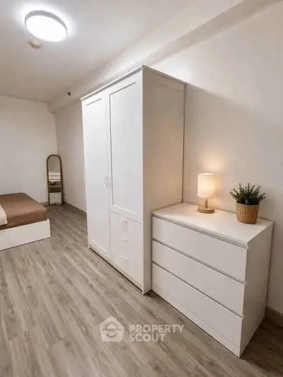 Modern minimalist bedroom with wooden flooring, white furniture, and cozy lighting.