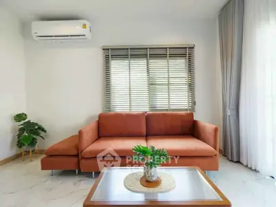 Modern living room with orange sofa, air conditioning, and stylish decor
