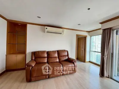 Spacious living room with leather sofa and large window offering city views.