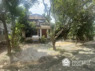 Charming rustic house surrounded by lush greenery and mature trees, offering serene natural ambiance.